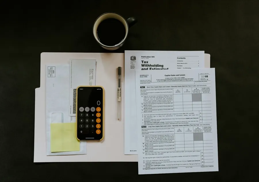 Household papers, a calculator, and a coffee cup on a desk.