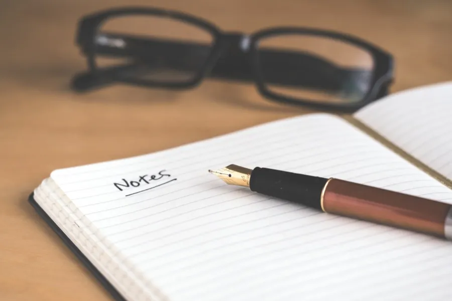 A notebook and pen on a desk in soft light.