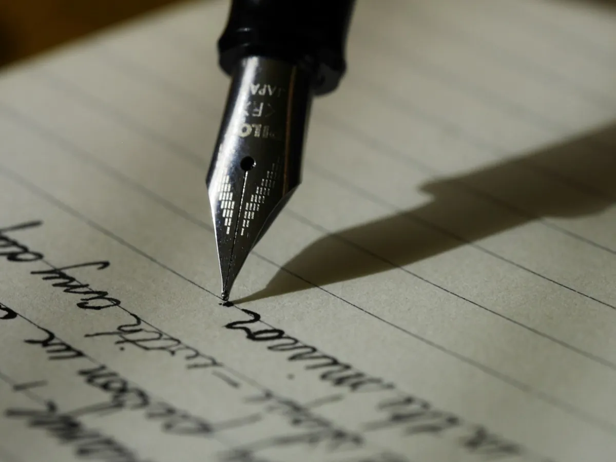 A person writing in a notebook with a pen.