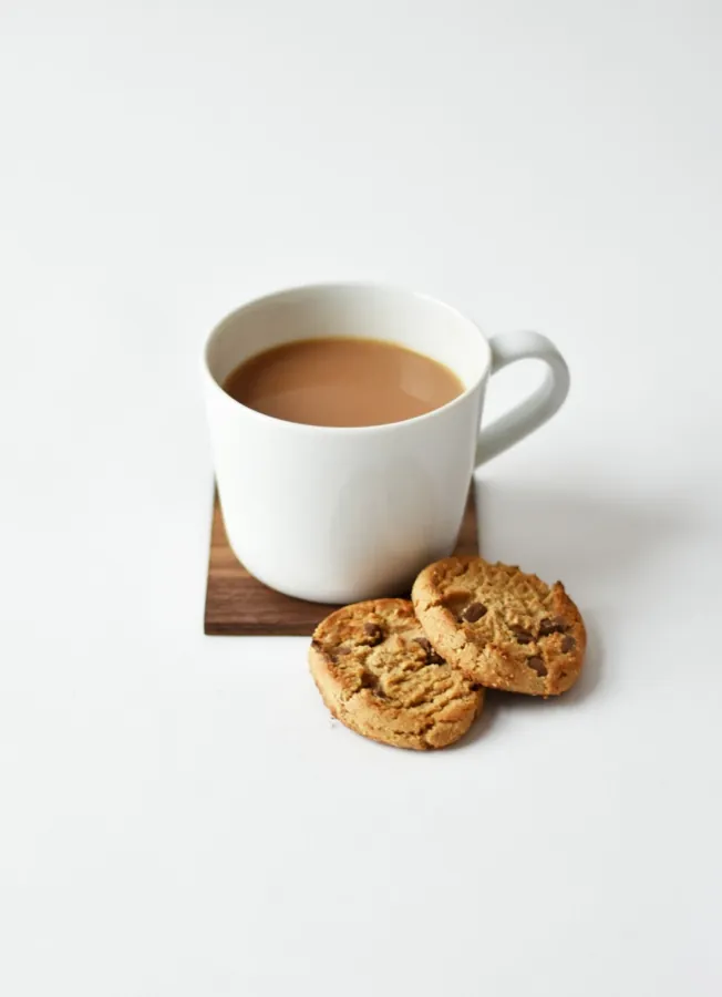 A warm drink and a small snack on a table.
